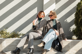 zwei Frauen sitzend in einer Wide leg Jeans in der sonne