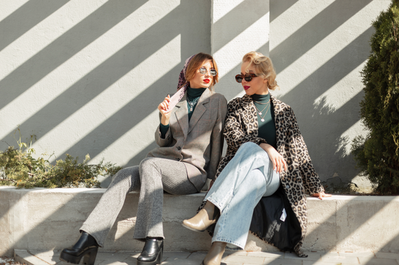 zwei Frauen sitzend in einer Wide leg Jeans in der sonne